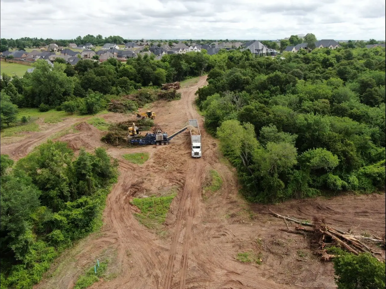 Aerial view of a right of way corridor cleared through timber toward an Oklahoma subdivision