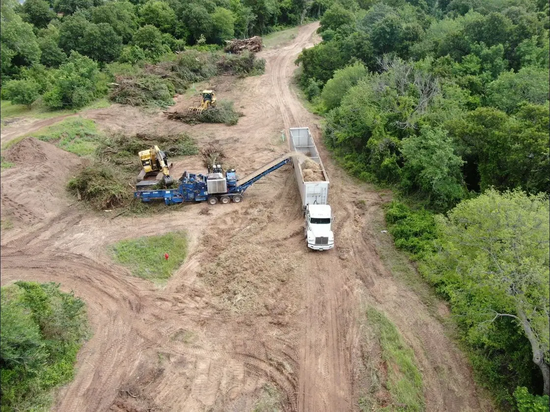 Aerial view of ROW clearing through Oklahoma woods with a grinder and haul truck working the corridor